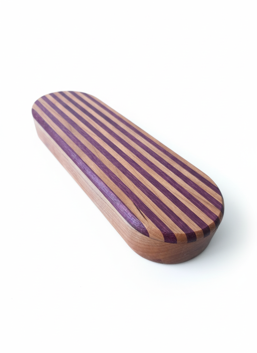 Oval-shaped wooden object with purple  heart and cherry wood stripes on top and a solid cherry wood bottom